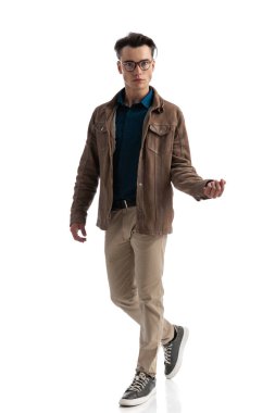 Kahverengi deri ceketli ve gözlüklü zeki bir adam beyaz arka planda izole edilmiş parmaklarını şıklatırken yan yana yürüyor.