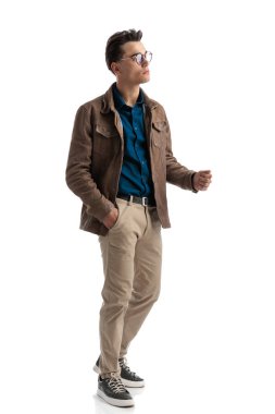 Çekici bir genç adam, elleri cebinde poz verirken baştan çıkarıcı ve yandan, tüm vücudunu gösteriyor.