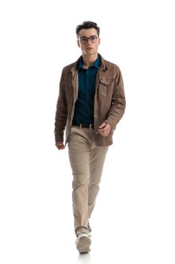 Deri ceketli, gözlüklü, beyaz arka planda yürüyen seksi bir genç.