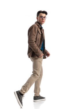 Deri ceketli çekici genç adam cebini tutarken yana doğru hareket ediyor.