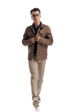 Yakışıklı, zeki, sıradan bir adam beyaz arka planda, kahverengi deri ceketi iliklerken öne çıkıyor.