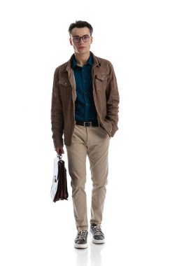 Rahat genç işadamı, elinde bir bavul beyaz arka planda el ele duruyor.