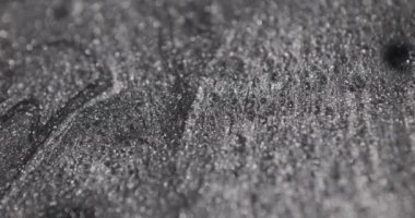 hareket eden, düşen ve birbirine karışan gümüş renkli resimler sanatsal dokular oluşturuyor.