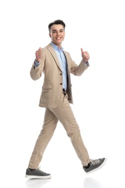 Beyaz arka plana basan ve bej bir takım elbise giyerken 