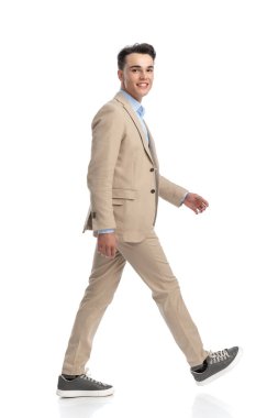 Beyaz arka plana basan bej takım elbiseli mutlu iş adamının yan görüntüsü.