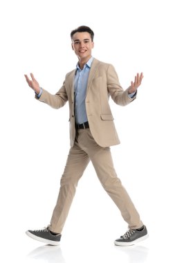 Genç bir işletme öğrencisi beyaz arka planda yürüyor ve merhaba jesti yapıyor.