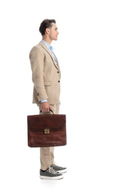 Takım elbiseli ve evrak çantalı bir işletme öğrencisi beyaz arka planda beklerken sırada bekliyor.