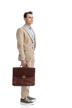 Bej takım elbiseli bir işadamının beyaz arka planda dikilirken yüzünü çevirmesi.