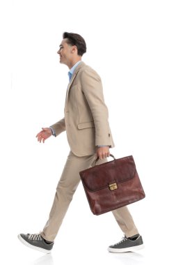 Bej takım elbiseli çekici, akıllı, sıradan bir adam. Elinde bavulla, gülümsüyor, uzun bir resmi var.