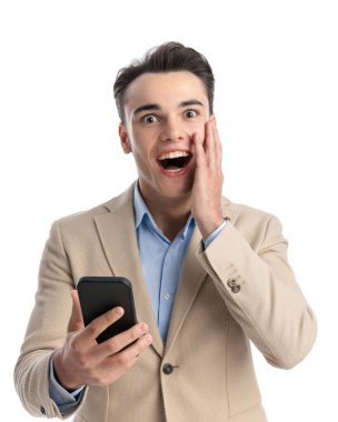 Telefonda piyango kazanan ve inançsızlıkla yüzüne dokunan heyecanlı genç işletme öğrencisinin yakın çekimi.