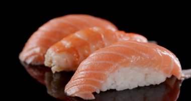 Güzel Japon yemeği, taze somon ve karidesli nigiri suşi. Yumuşak pirinçli ve siyah arka planda hareket eden bir tabakta.