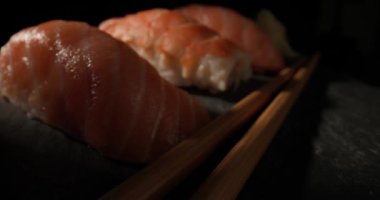 Üç lezzetli karides ve somonlu nigiri suşinin yanında çubuk var.