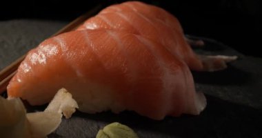 Üç somon nigiri suşi, turşulu zencefil, wasabi ve yemek çubuğu.