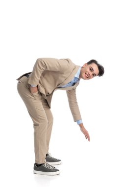 Beyaz arka planda cebini tutarken yerden bir şey yükselten rahat iş öğrencisinin yan görünüşü