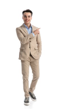 Rahatlamış öğrenci beyaz arka planda yürüyor ve parmağıyla sağa sola işaret ediyor.