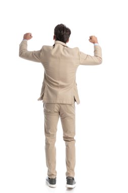 Genç, zeki, sıradan bir adamın arkadan görünüşü havada yumruklarla kutlama yapıyor, tüm vücuduyla.