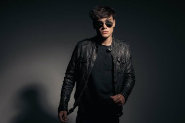 Siyah deri ceket ve güneş gözlüğü takan seksi erkek modelini yakın plan.