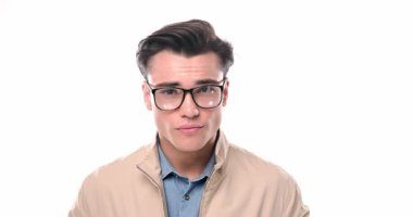 Gözlüklü seksi genç adam ileri bakıyor, dönüyor ve beyaz arka planda yürüyor.