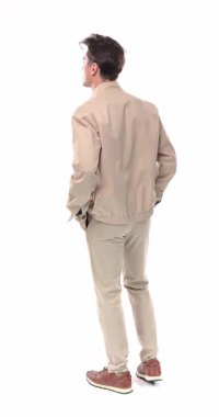 Ceketi düzenleyen, ellerini cebine sokup, beyaz arka planda hareket eden genç bir adamın arkadan görünüşü.