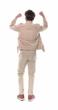 Dikey videoda, heyecanlı genç adam kameranın karşısında dikiliyor ve beyaz arka planda yumrukları havada zafere tezahürat yapıyor.