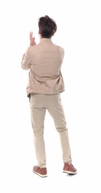 Bej elbiseli sıradan bir gencin arka plan görüntüsü. Stüdyoda beyaz arkaplan önünde ayakta alkışlıyor.