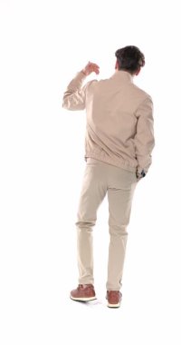 Elle hareket eden genç bir adamın arka plan görüntüsü. Arkasını dönüyor, gülümsüyor ve beyaz arkaplan önünde kollarını kavuşturuyor.