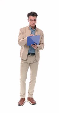 Yakışıklı genç adam pano tutuyor, notlar alıyor, el sallıyor, gülümsüyor, başparmak işareti yapıyor ve beyaz arka planda yürüyor.