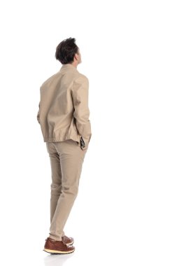 Bej renkli ceketli, spor ayakkabılı, cebinde el ele tutuşan ve beyaz arka plana bakan sıradan bir adamın arka planı.