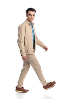 Beyaz arka planda yürüyen ve baştan çıkarıcı bir şekilde ileriye bakan seksi, mutlu adamın yan görünüşü.