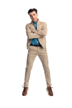 Bej ceketli genç adam kollarını kavuşturuyor, gülümsüyor ve beyaz arka planda havaya zıplıyor.