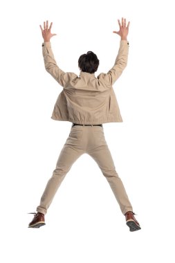 Kollarını başının üstünde tutan ve beyaz arka planda havaya zıplayan sıradan bir gencin arka plan görüntüsü.