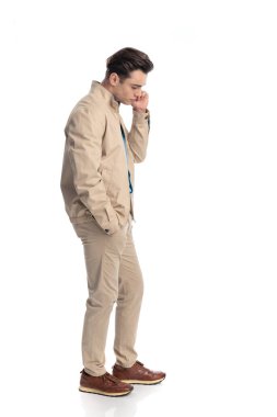 Yüze dokunan, el ele tutuşan ve beyaz arkaplana bakarken düşünen seksi genç adamın yan görüntüsü