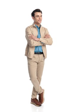 Mutlu sıradan bir adam kollarını kavuşturup beyaz arka planda dururken yan yana bakıp gülümsüyor.