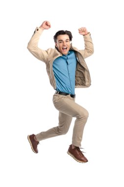 Kafasının üstünde yumrukları olan heyecanlı sıradan bir adam beyaz arka planda çığlık atıyor ve havaya zıplıyor.