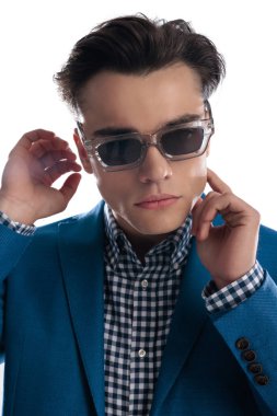 Modern güneş gözlüklü kötü adam portresi. Yüze dokunuyor ve beyaz arka planda havalı bir şekilde poz veriyor.