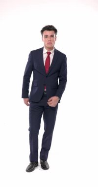 Seksi moda adamı yürürken lacivert takımını ilikliyor, el ele tutuşuyor ve ileriye bakıyor, yan bir poz veriyor ve kollarını kavuşturmadan önce avuç içini ovuyor.