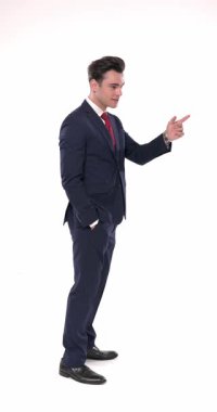 Lacivert takım elbiseli zarif iş adamının yan görünüşü. Ellerini cebine sokmadan önce parmak hareketi yapıyor.