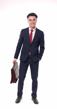 Lacivert takım elbiseli mutlu bir adam, beyaz arka planda yürümeden önce saati kontrol ediyor ve eliyle başını sallıyor.