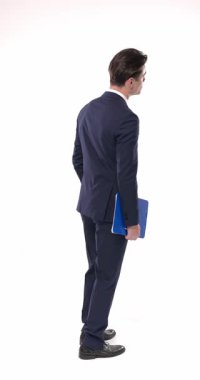 Arkaya bakan genç işadamlarının arka planı, elinde pano, saati kontrol eden, beyaz arka plana bakan ve ayakta duran.