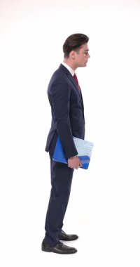 Yakışıklı iş adamının yan görünüşü. Sıraya girmiş, saati kontrol ediyor, arkasına bakıyor ve beyaz arka planda gülümsüyor.