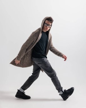 örgülü kapüşonlu, gözlüklü ve beyaz arka planda poz veren dinamik genç adam.