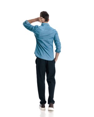 Kafası karışmış mavi kot gömlekli genç adam kafasını kaşıyor, merak ediyor ve onunla yürüyor. 