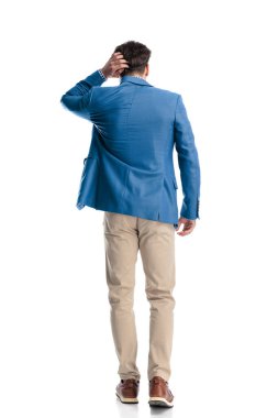 Kafası karışmış genç bir adamın beyaz arka planda yürürken kafasını kaşıması ve düşünmesi.