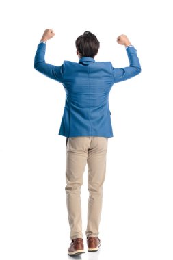 Mavi ceketli, kafasında yumruklar olan hevesli bir adam beyaz arka planda yürürken kutlama yapıyor.