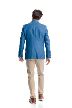 Stüdyoda beyaz arka planda yürüyen mavi ceketli, akıllı, sıradan bir adamın arka plan görüntüsü.