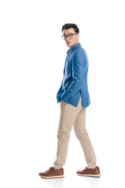 Beyaz arka planda elleri ceplerinde hareket eden, gözlüklü seksi, akıllı, sıradan bir adamın yan görüntüsü.