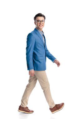 Mavi ceketli, beyaz arka planda gülümseyen ve yürüyen gururlu genç adamın yan görüntüsü.