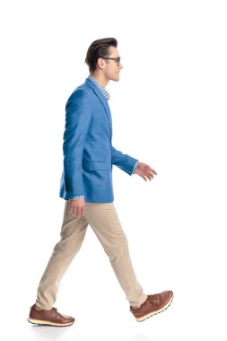 Mavi ceketli, yandan bakan, gülümseyen ve beyaz arka planda yürüyen mutlu genç bir adam.