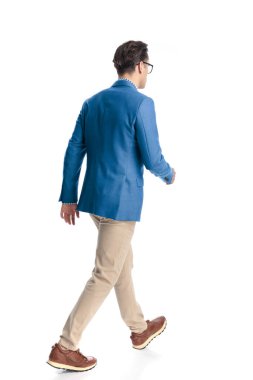 Mavi ceketli, beyaz arka planda yürüyen sıradan bir genç adamın tüm vücudunun resmi.