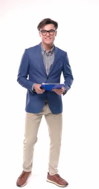 Gözlüklü sıradan bir genç öğrenci, notlar alıyor ve stüdyoda beyaz arkaplan önünde gülümsüyor.